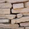 Austin Flagstone limestone blocks stacked in layers, showcasing rough textures and natural beige-gray coloration for landscaping and construction in Texas.