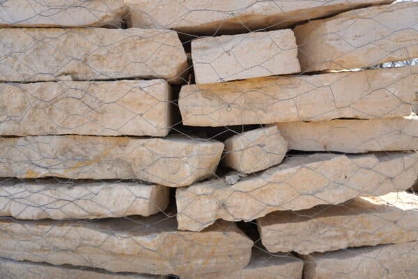 Austin Flagstone limestone blocks stacked in layers, showcasing rough textures and natural beige-gray coloration for landscaping and construction in Texas.