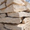 Austin Flagstone limestone blocks stacked in layers, showcasing rough textures and natural beige-gray coloration for landscaping and construction in Texas.
