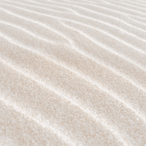 Close-up of fine white sand ripples with a soft, natural texture, showing delicate wind-swept patterns.