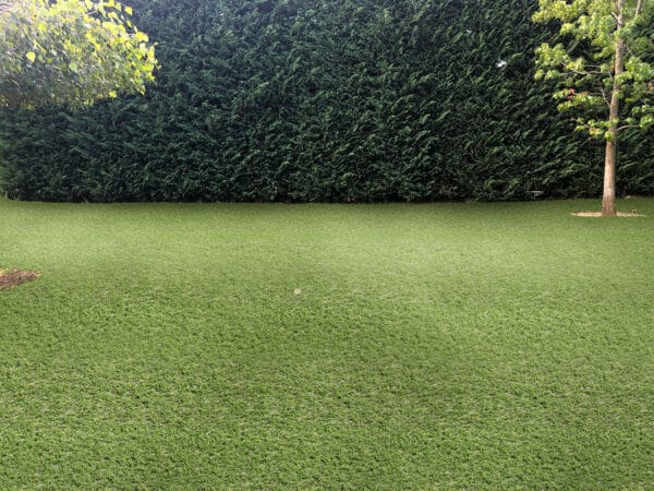 Emerald Green Turf 76 roll with vibrant synthetic grass and black woven backing, used for landscaping and sports applications in Texas.